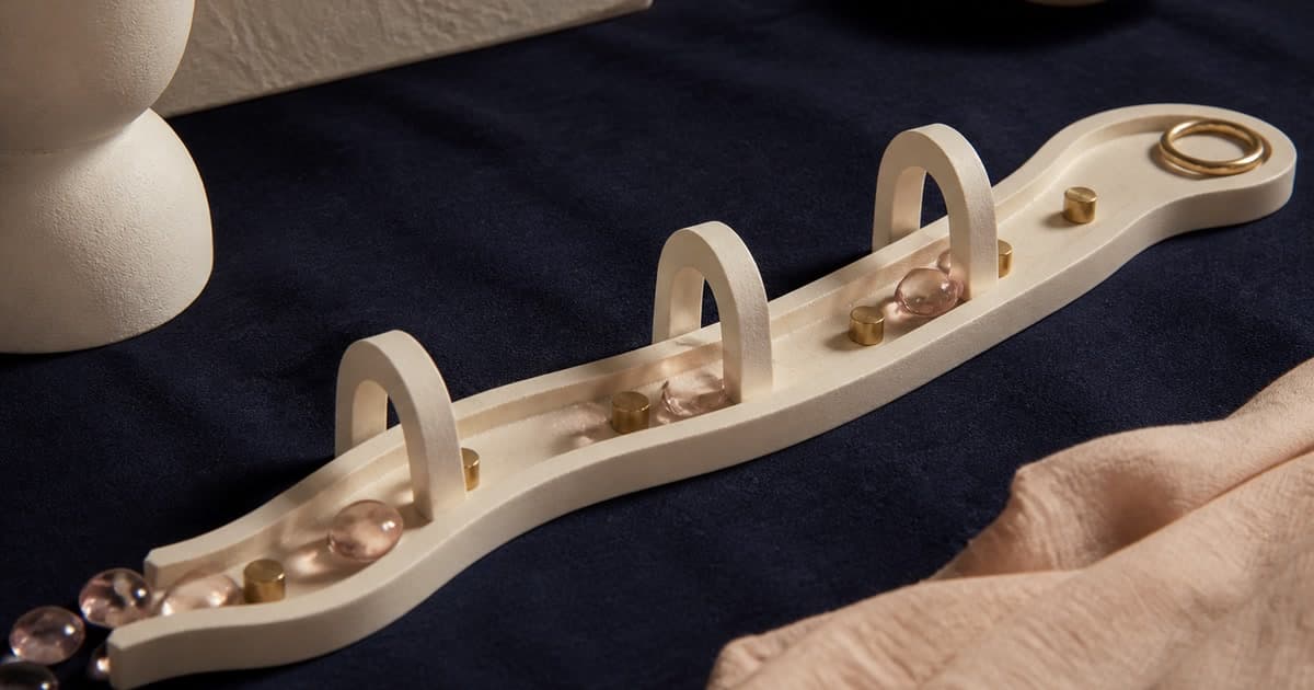 A sculptural cream timeline curves across indigo linen through ceramic arches, with gold markers and blush glass pebbles showing money moving between dates.